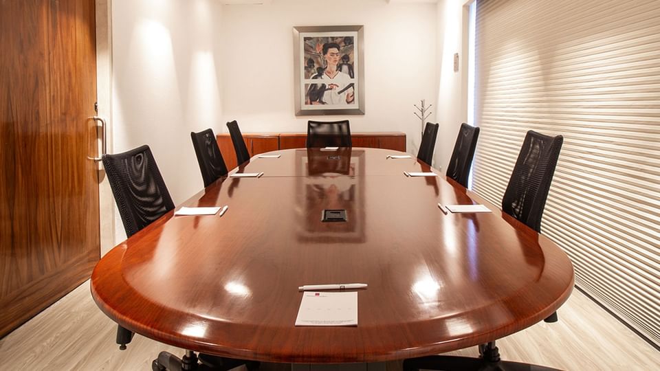 Corporate boardroom setup featuring a large oval wooden table at Camino Real Aeropuerto Mexico