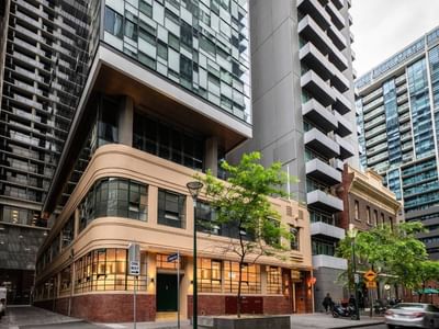 Modern buildings and skyscrapers in an urban area with cars, trees, and a narrow street.