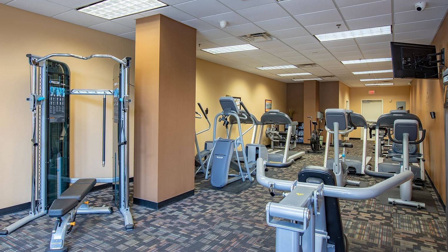 A well-equipped gym with various exercise machines and a TV