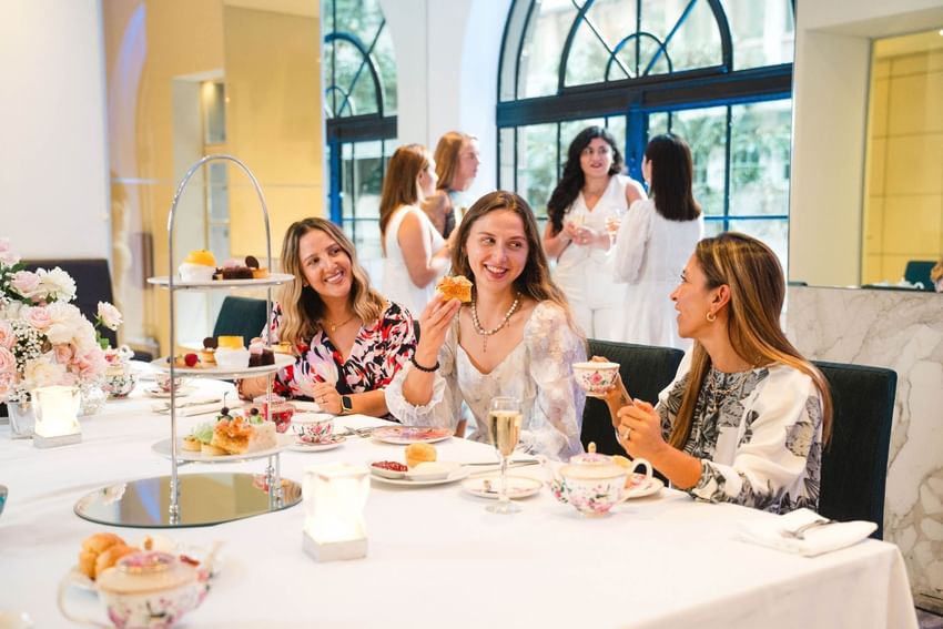 Friends gathered around a high tea platter with sweets and tea at Paradox Sydney near restaurants near sydney opera house