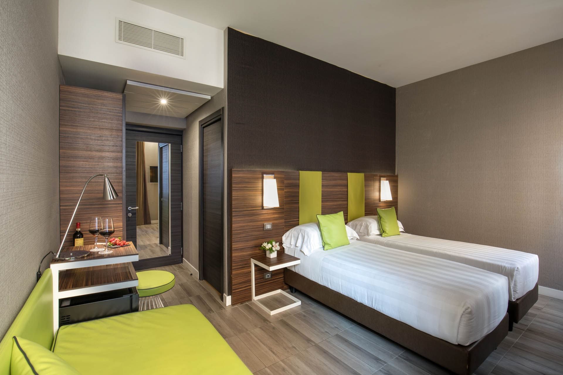 Superior Room featuring two twin beds, stylish decor with green accents, a small seating area at The Republic Hotel