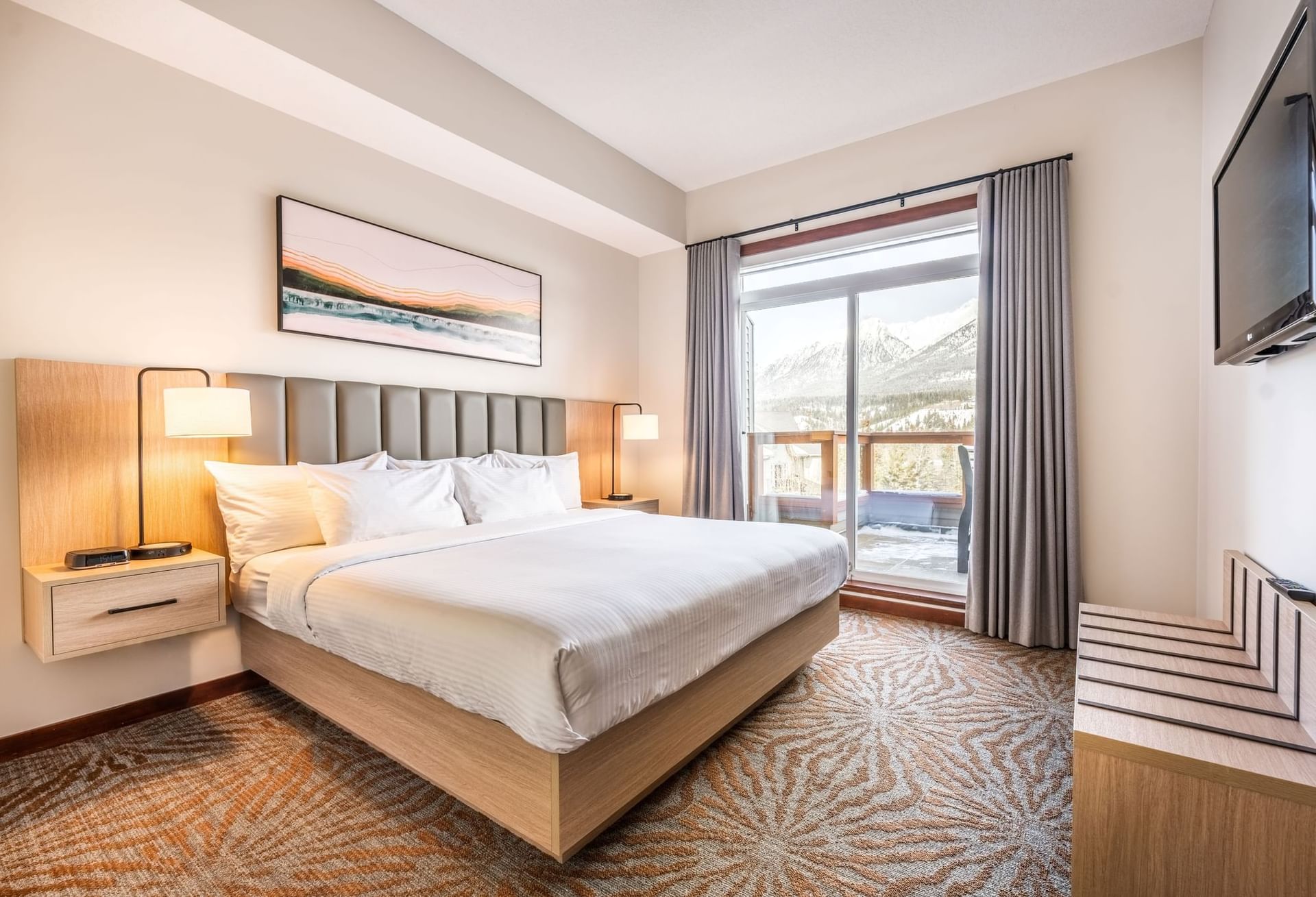 Comfy bed by the window and a TV in the Mountain View Suite at Blackstone Mountain Lodge