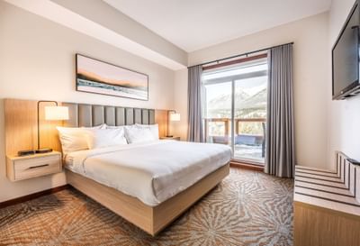 Comfy bed by the window and a TV in Two Bedroom Mountain View Suite at Blackstone Mountain Lodge