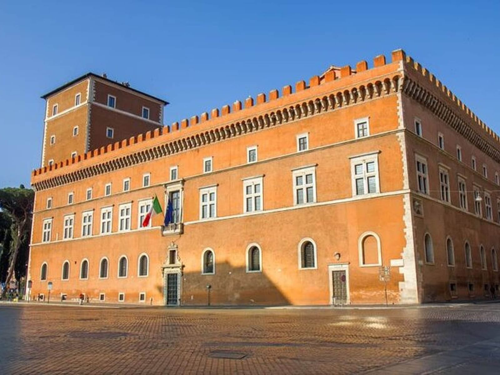 National Museum of the Palazzo di Venezia with orange façade and crenellated roof near The Glam Hotel