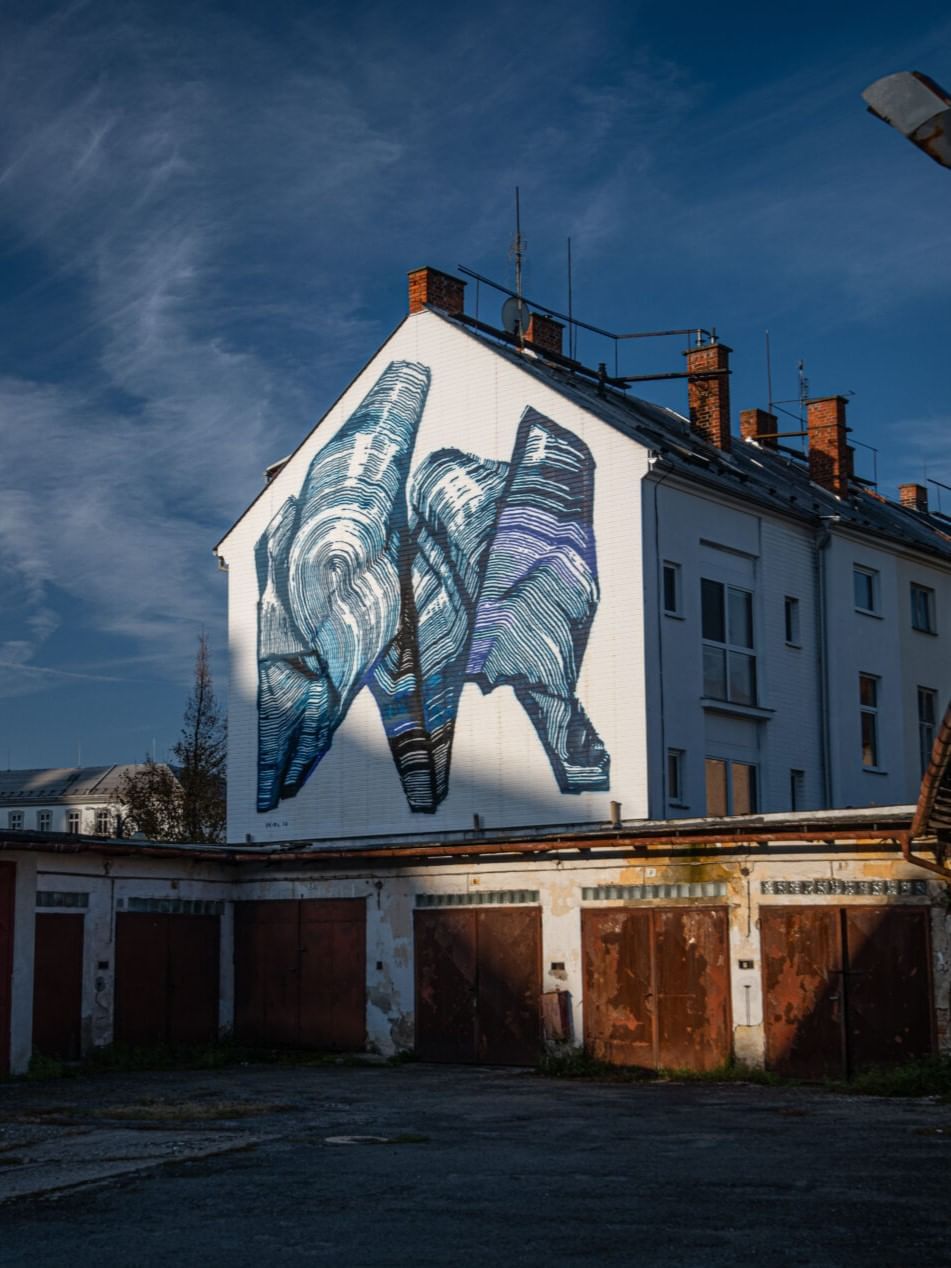 Mural of abstract fingers on building facade above rustic garages near Almanac Palais Vienna