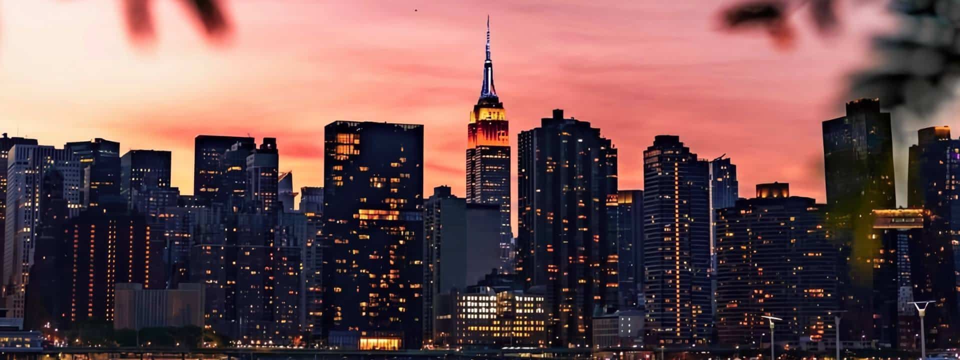 A city skyline at sunset with skyscrapers and evening lights.