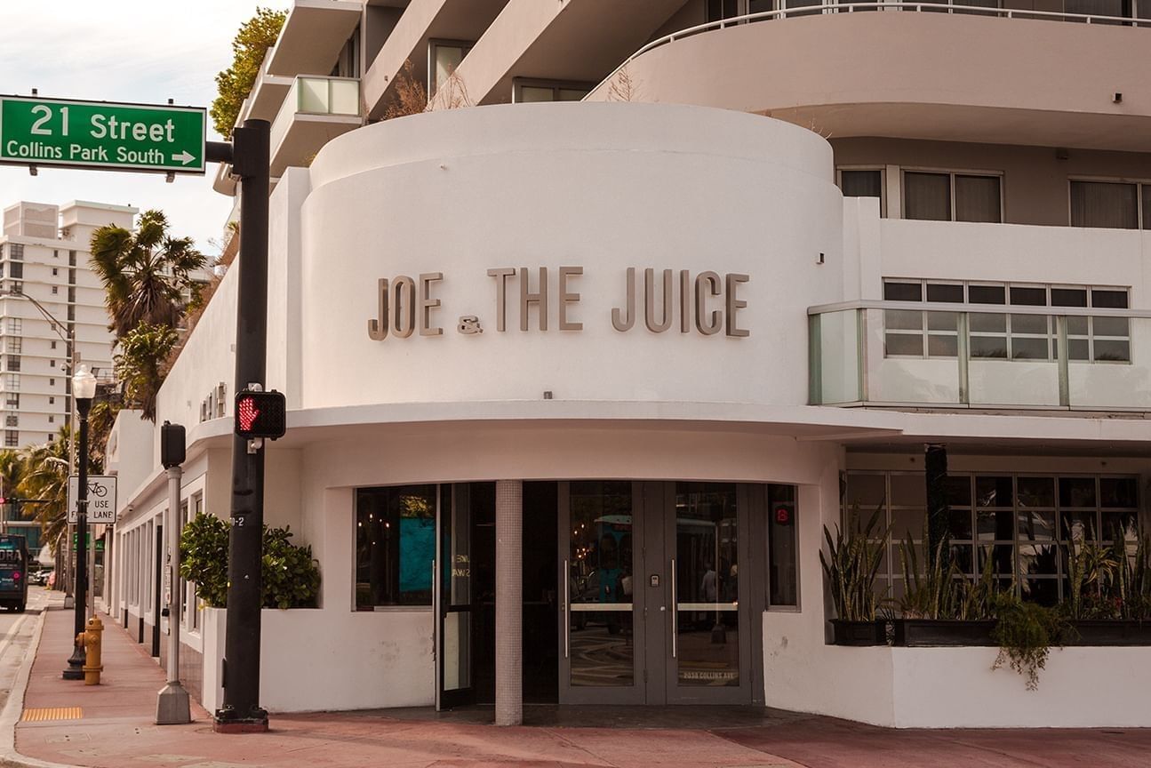 A white building with a sign reading 'JOE THE JUICE' on a street corner.