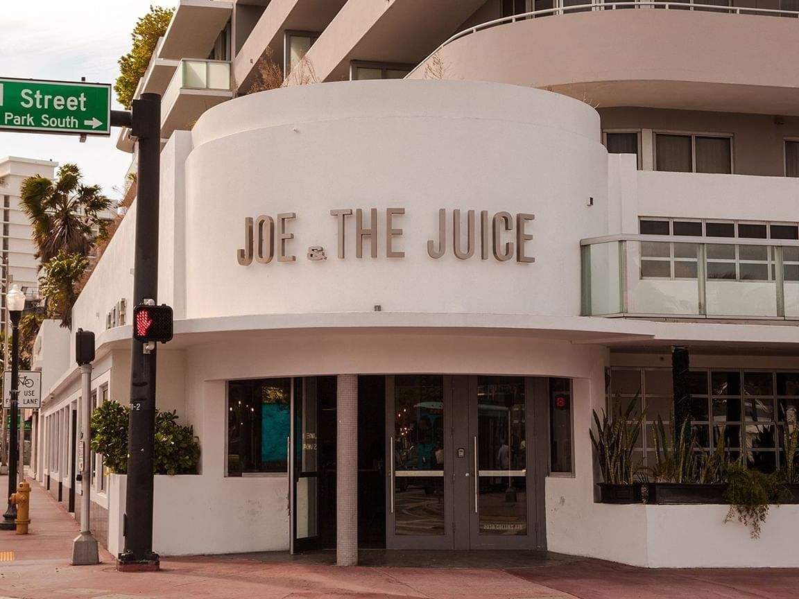 White Art Deco Joe & The Juice exterior on a street corner with a green street sign near Crest Hotel & Suites