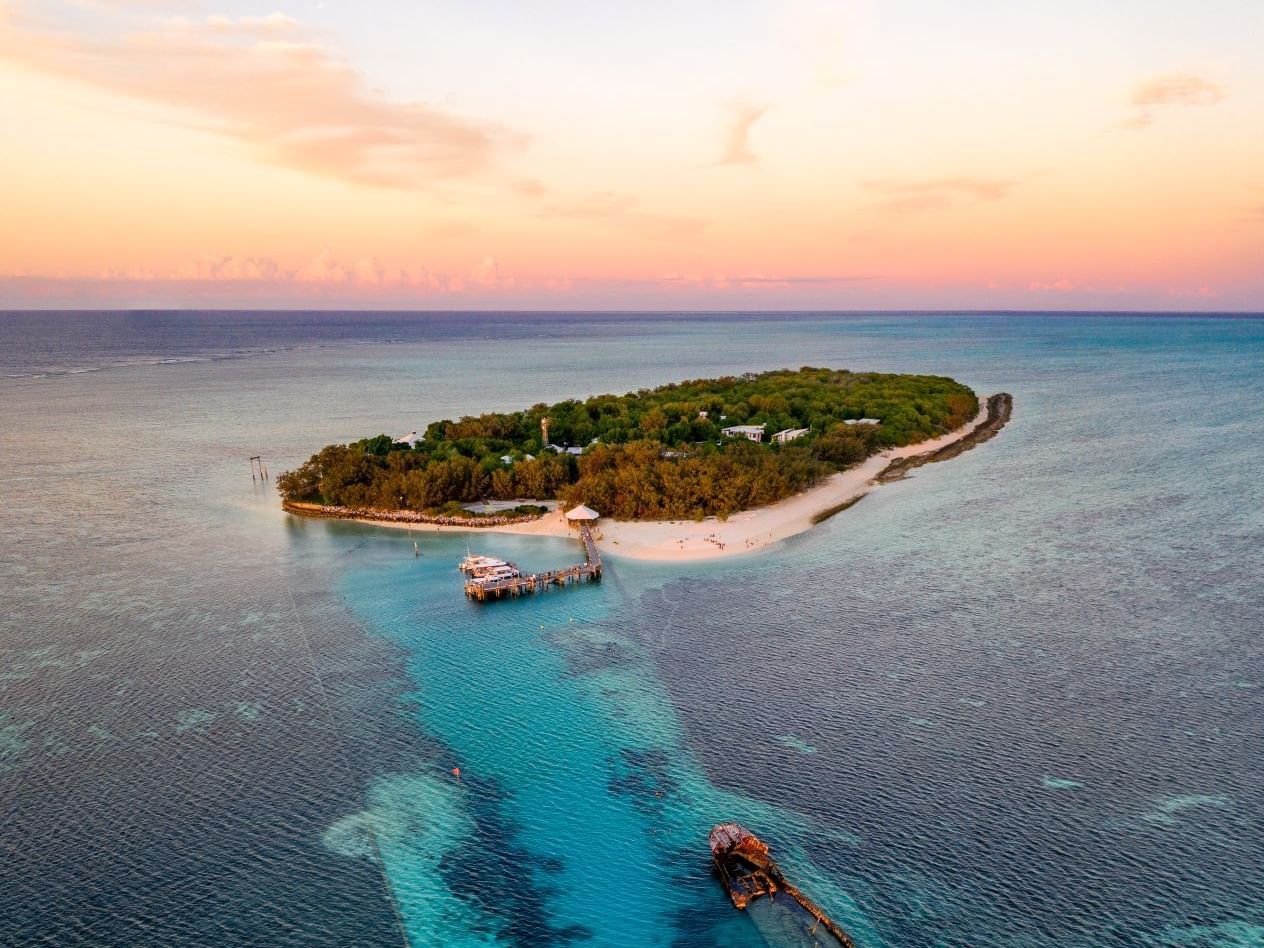 Aerial view of a tropical island resort surrounded by turquoise ocean at sunrise near Heron Island Resort