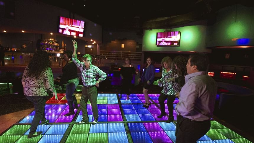 Personas disfrutando de la música en una pista de baile iluminada y colorida en El Rollo de Araiza Palmira