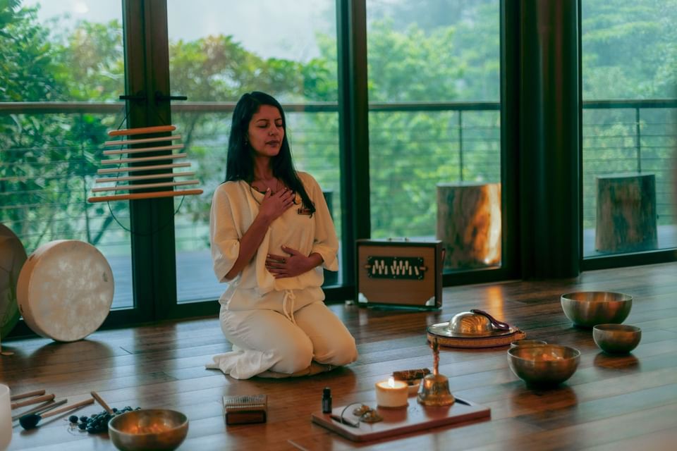 Lady meditating with singing bowls and candles in Wellness Center at El Silencio Lodge & Spa