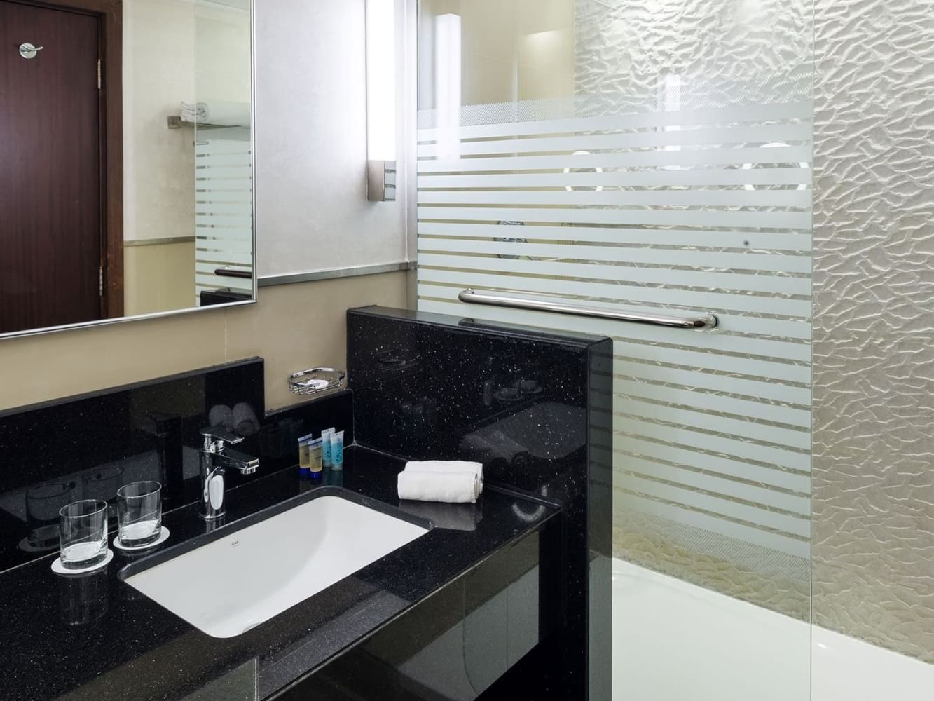 Modern bathroom with a sink, mirror, and glass shower at Saja by Warwick Madinah.
