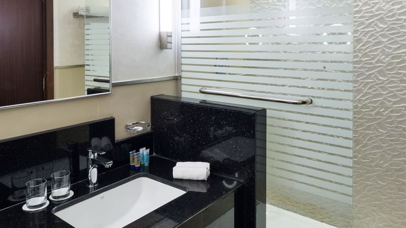 Modern bathroom with a sink, mirror, and glass shower at Saja by Warwick Madinah.