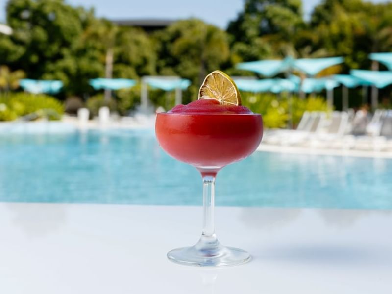 Close-up of red cocktail with a lime garnish by a pool at Crown Hotels