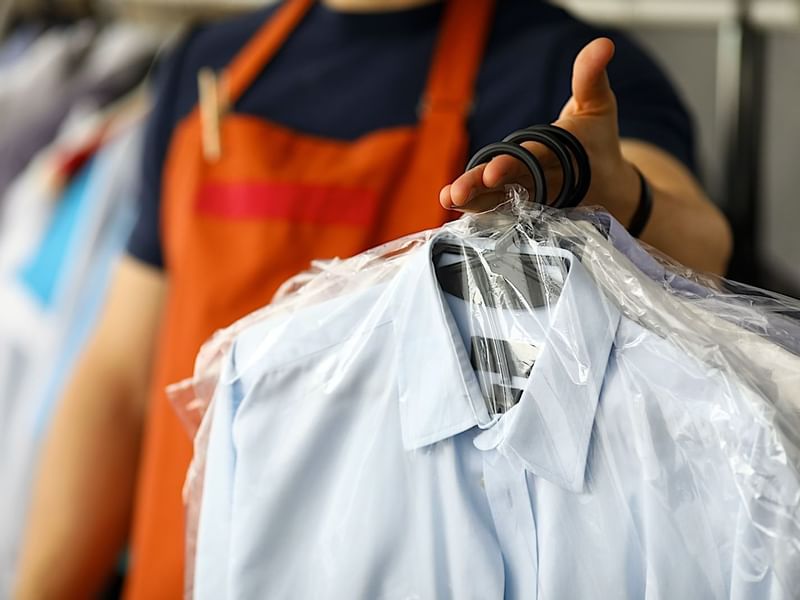 Hotel staff member at El Prado Hotel providing dry cleaning service with a freshly pressed shirt
