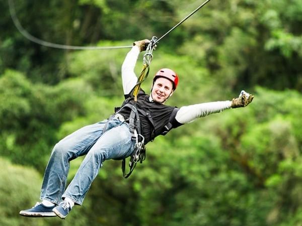 Man ziplining down the forest at South Shore Canopy near Paradise Beach Hotel