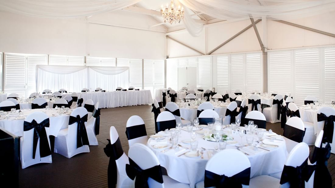 Receptions banquet hall set for a event, featuring tables, draped fabric, and a chandelier at Mercure Hotel Townsville