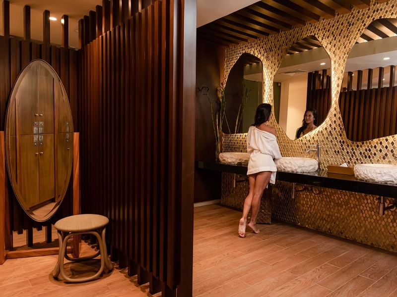 A woman looking into a mirror in Okom spa at The Reef 28