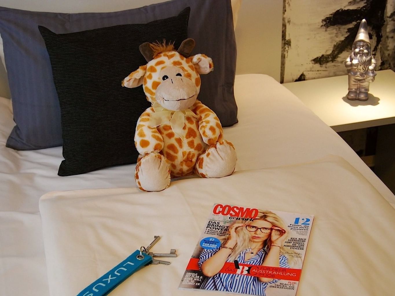 Soft toy and a magazine on a bed at Rheinland Hotel Kollektion