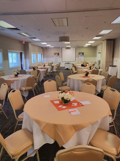 Sutter Room featuring round tables with peach tablecloths and floral centerpieces at Lake Natoma Inn