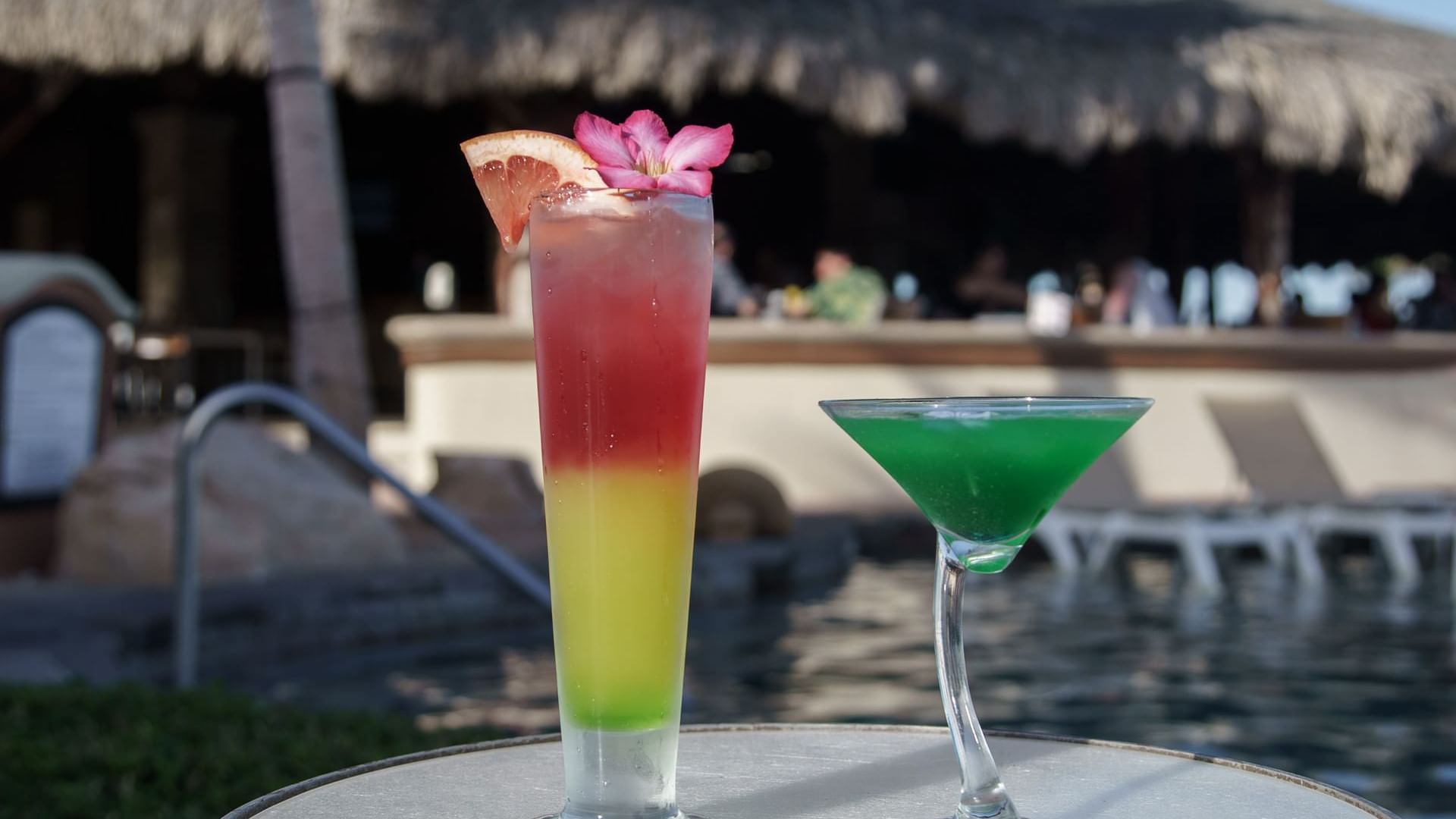 Layered cocktail and a green martini on a table by the pool at Sirenas Restaurant in Hacienda del Mar Los Cabos.