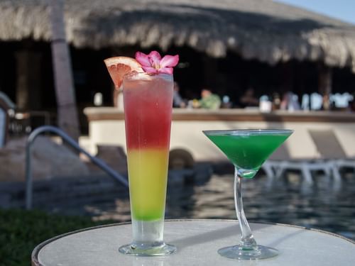 Layered cocktail and a green martini on a table by the pool at Sirenas Restaurant in Hacienda del Mar Los Cabos