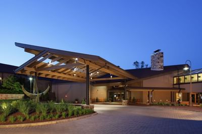 Modern conference center entrance with illuminated timber canopy and brick driveway at Aramark Chauncey Conference Center