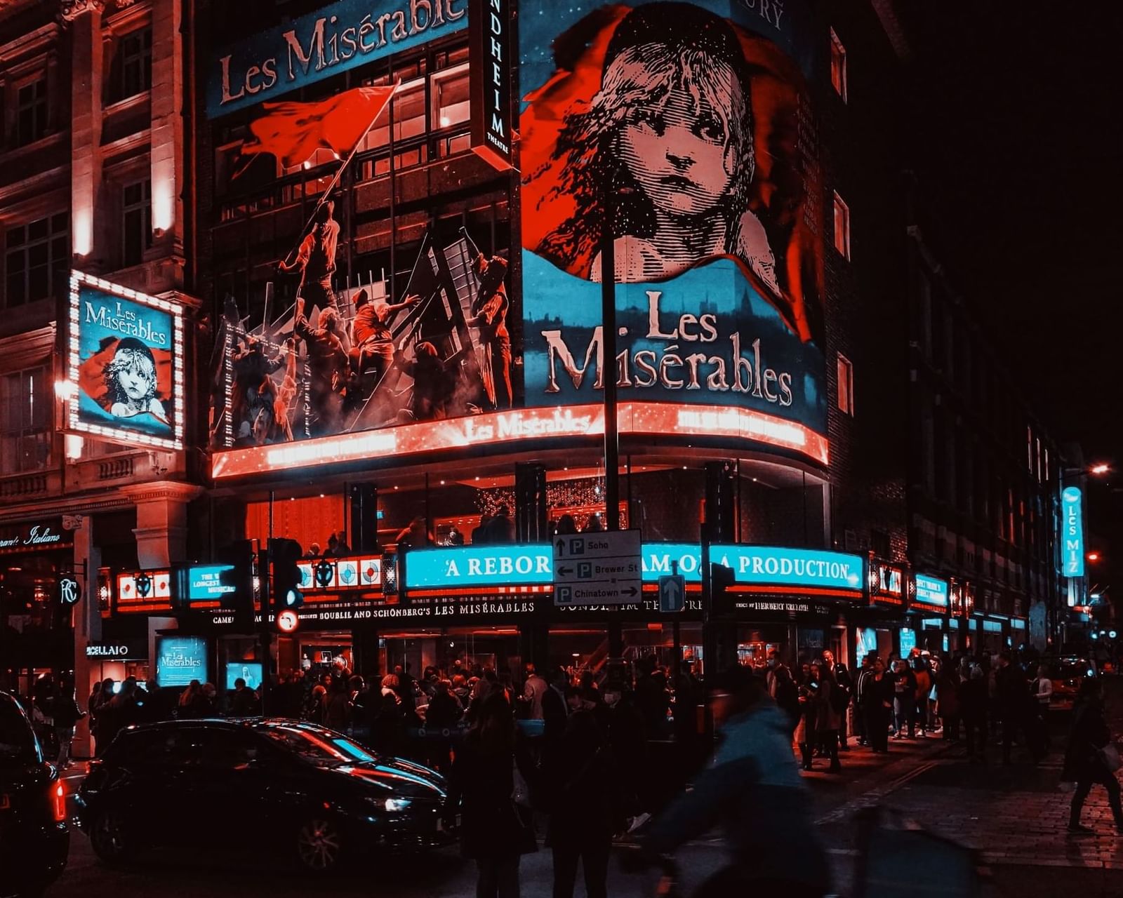 Queen's Theatre at Night with full of crowded streets near The Londoner Hotel