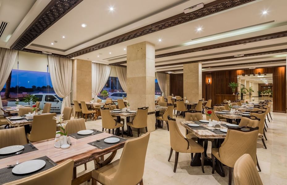 Royal Restaurant with tan chairs by marble tables under a coffered ceiling at Naviti by Warwick Al Khobar