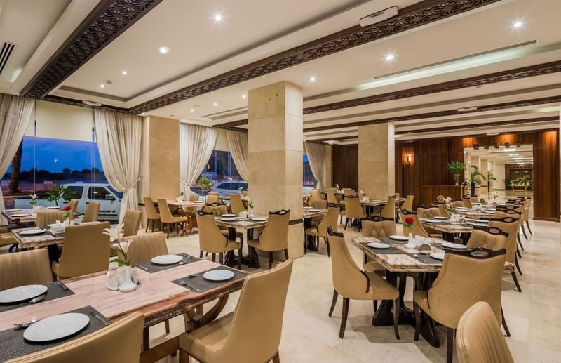 Royal Restaurant with tan chairs by marble tables under a coffered ceiling at Naviti by Warwick Al Khobar