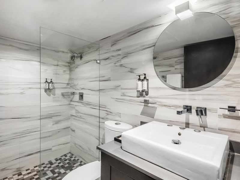 Junior Suite Vista Parcial Al Mar bathroom featuring marble tiles, a round mirror, and a glass shower at Sunvivia Mazatlán
