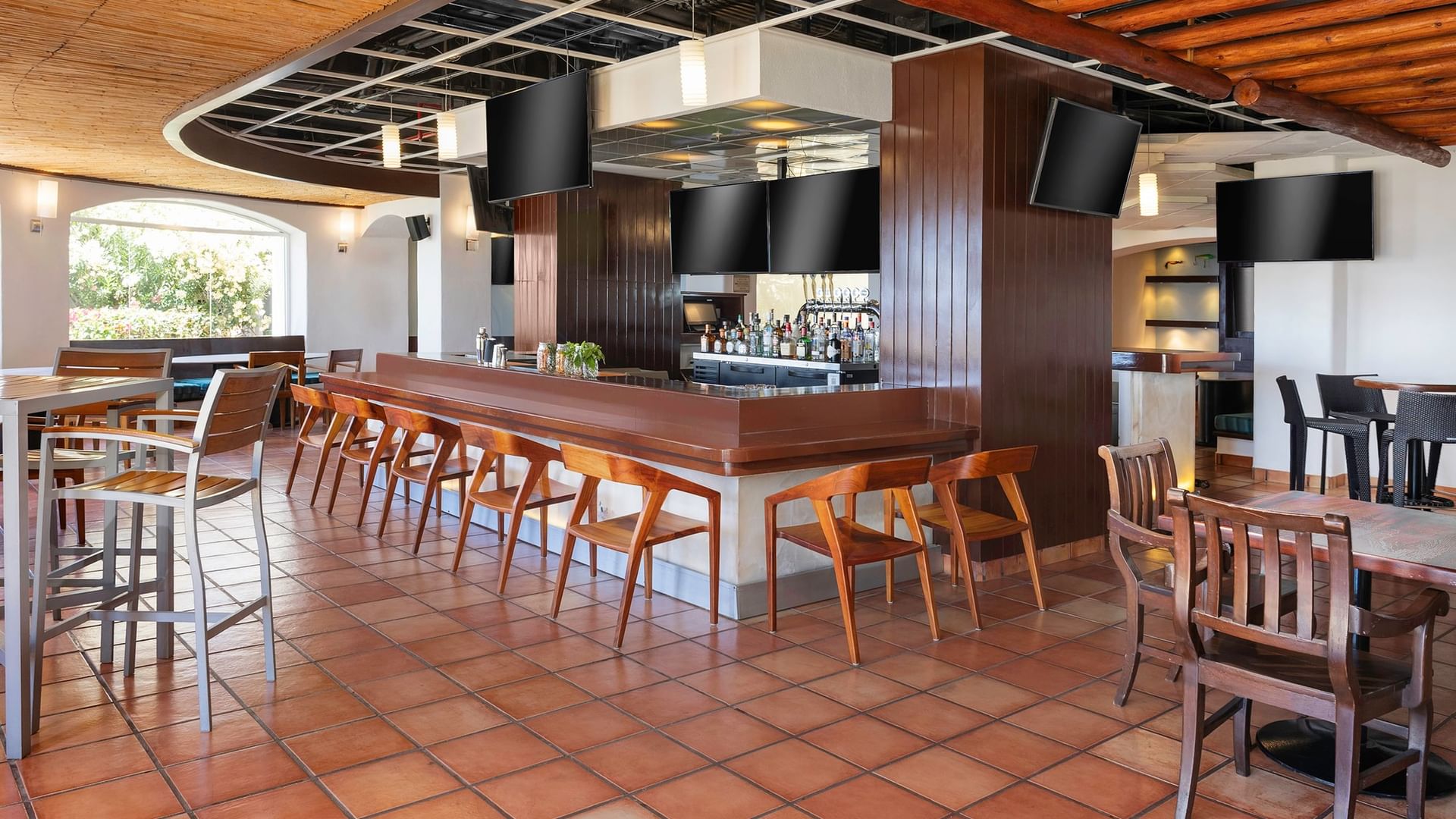 Sports Bar with wooden barstools, a terra cotta tiled floor, and TV screens at Hacienda del Mar Los Cabos