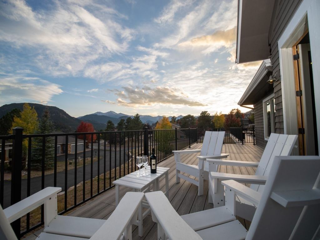Vacation Rental 408 outdoor patio with white chairs and a wine bottle on the table at The Stanley Hotel