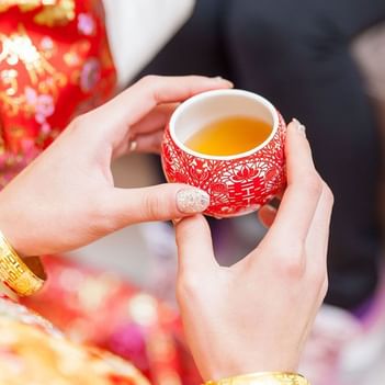 Close-up of a woman holding a Chinese red teacup at The Saujana Hotel Kuala Lumpur