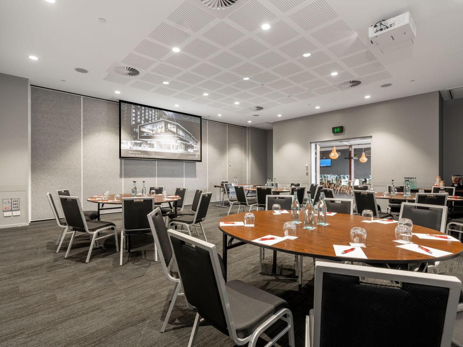 Contemporary conference room in Brisbane with cabaret-style seating, presentation screen, and event facilities at Hotel Grand Chancellor Brisbane.