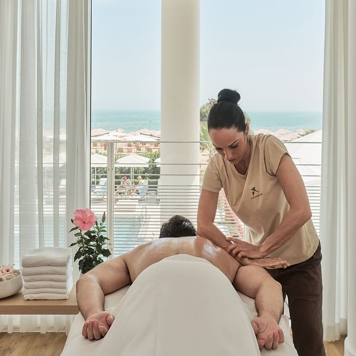Therapist giving a massage to a man at Falkensteiner Jesolo