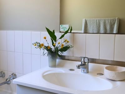 Clean bathroom with white sink, flowers, and towel at La Trobe University - Terraces.