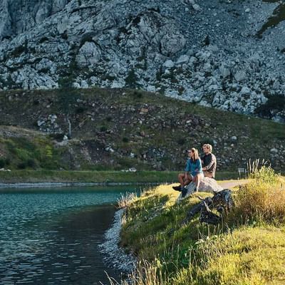 A couple sitting by the lake near Falkensteiner Hotels