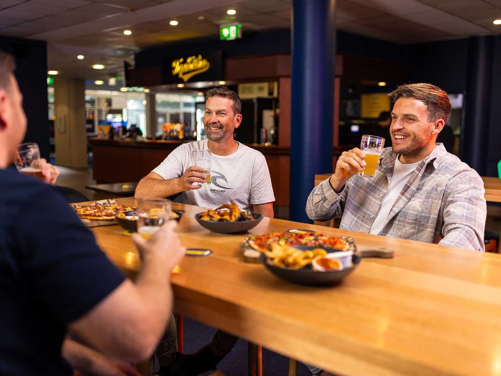 Three men enjoying drinks and food at Legends Taphouse  bar at Encore by Mingara