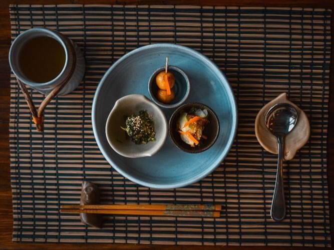 Japanese meal with green tea, chopsticks, and a spoon on a bamboo mat in Mako’s Restaurant at Dwarika's Himalayan Wellbeing