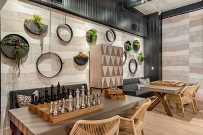 24-Hour Lounge with Games featuring a Chess set on the table, seating, and a lush wall decor at The Riverwalk Plaza Hotel