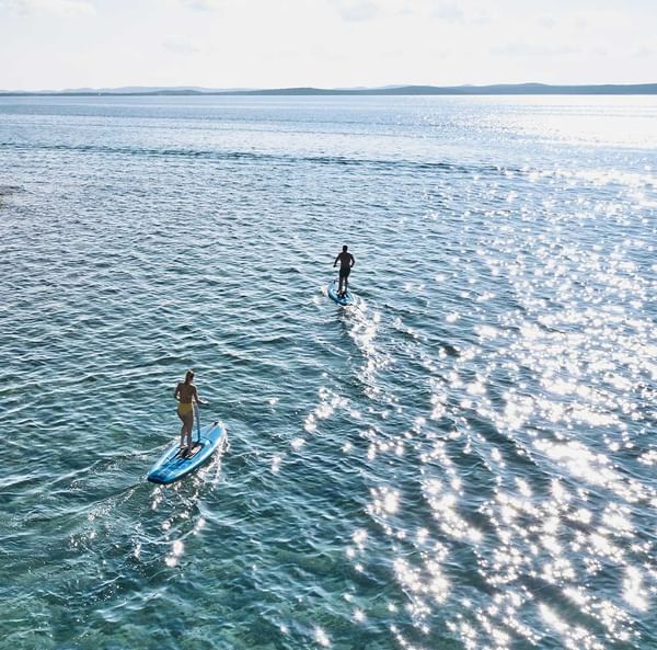 Aerial view of couple paddleboarding in the sea near Falkensteiner Hotels & Residences