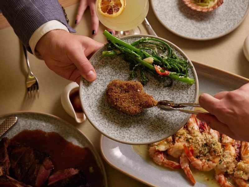 Person enjoying a  gourmet meal with meat & prawns in Modo Mio at Crown Metropol Perth