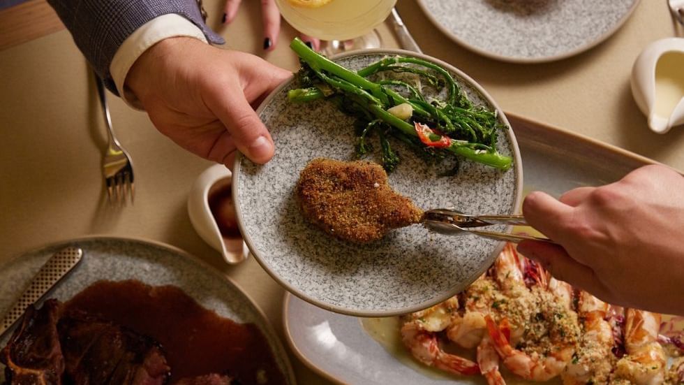 Person enjoying a  gourmet meal with meat & prawns in Modo Mio at Crown Metropol Perth