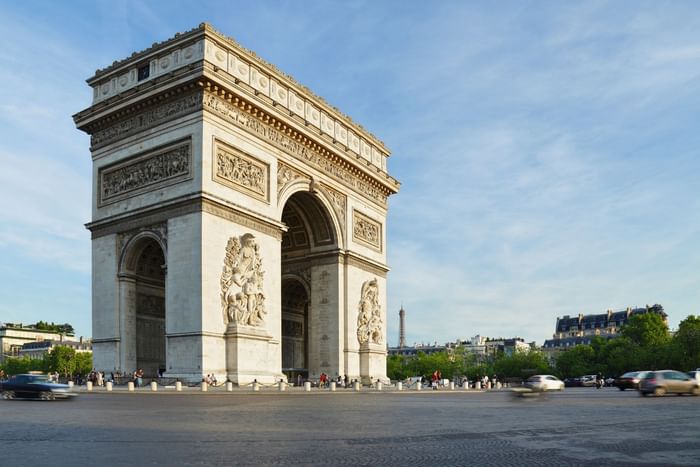 The Arc de Triomphe by a busy street under a clear blue sky near the Warwick Paris Champs Elysées