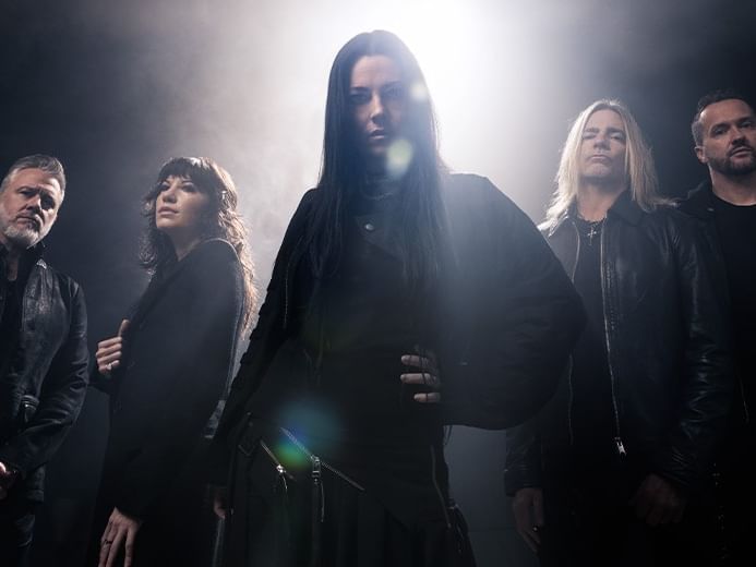 Five band members dressed in black stand dramatically backlit by bright stage lights for Evanescence World Tour 2027