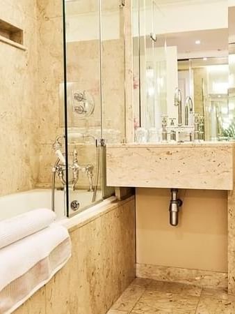 Junior-suite bathroom featuring a marble vanity with a bathtub at The Capital Hotel, Apartments and Townhouse