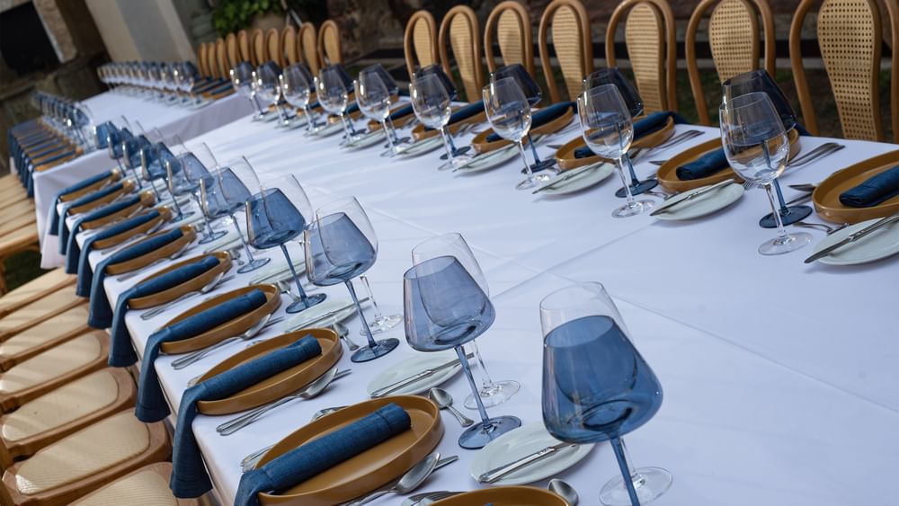 Long outdoor dining table with white linen, blue napkins, and wine glasses at Quinta Real Oaxaca