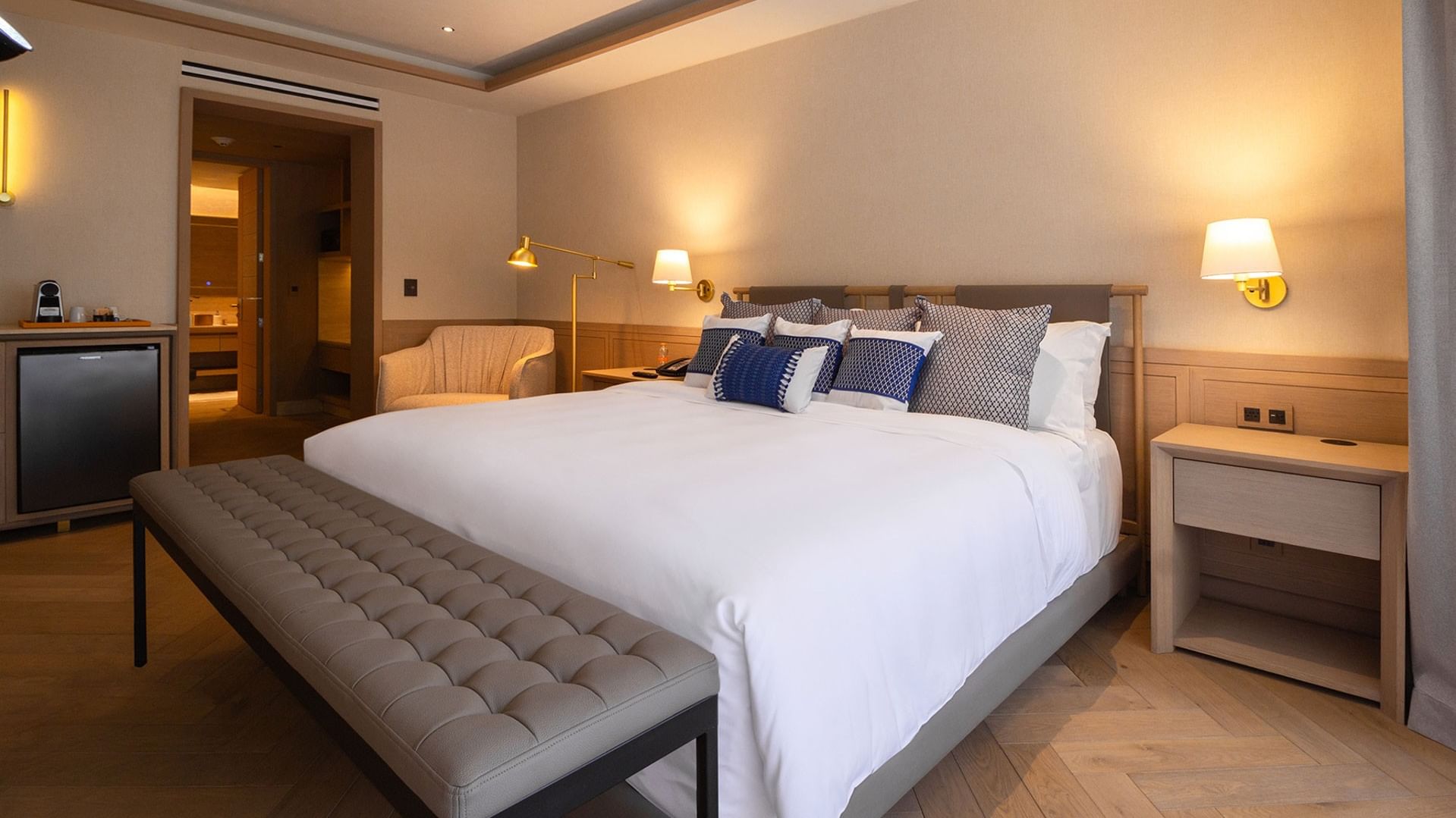 Suite King Superior Viceroys con cojines azules, banco gris e iluminación cálida en Camino Real Polanco México