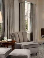 Grey armchairs and a table with coffee by a window under a standing lamp in Deluxe King Accessible at Warwick Melrose Dallas